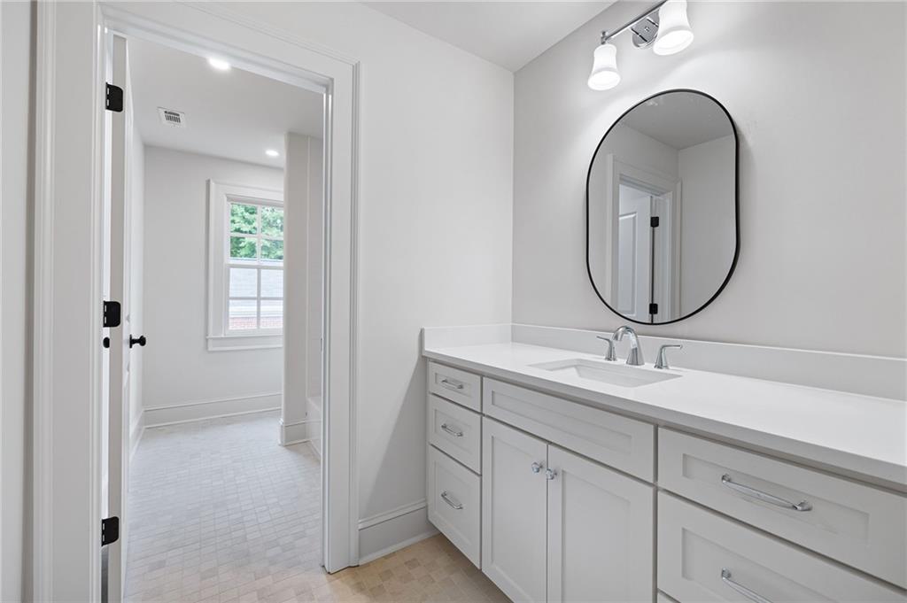 Bathroom with a long white vanity, double sinks, and a large oval mirror.