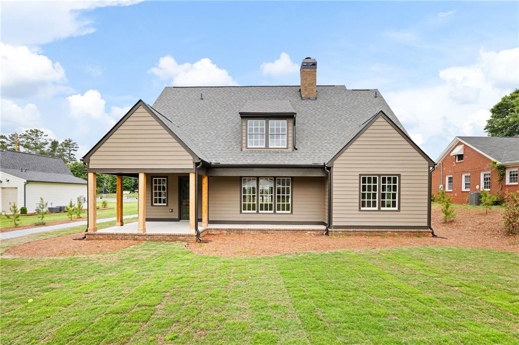 Two-story beige house with a covered porch and broad lawn.