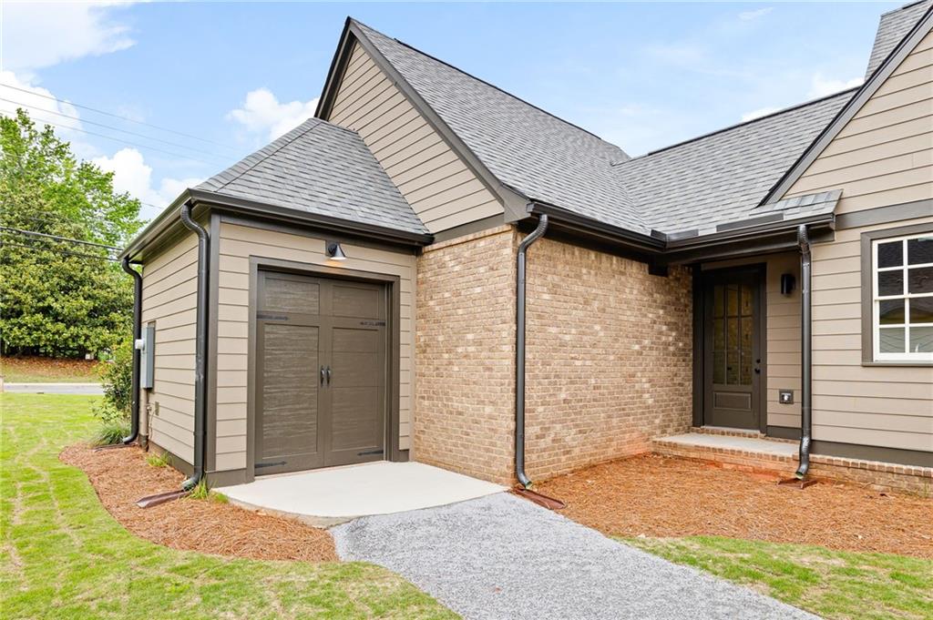 Home exterior with a brick entry, attached garage, and gray siding.