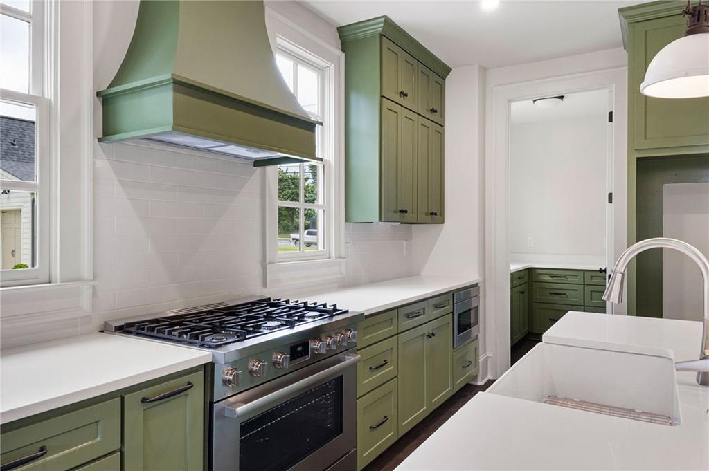 Kitchen with sage-green cabinets, a stainless steel gas range, and a white farmhouse sink.