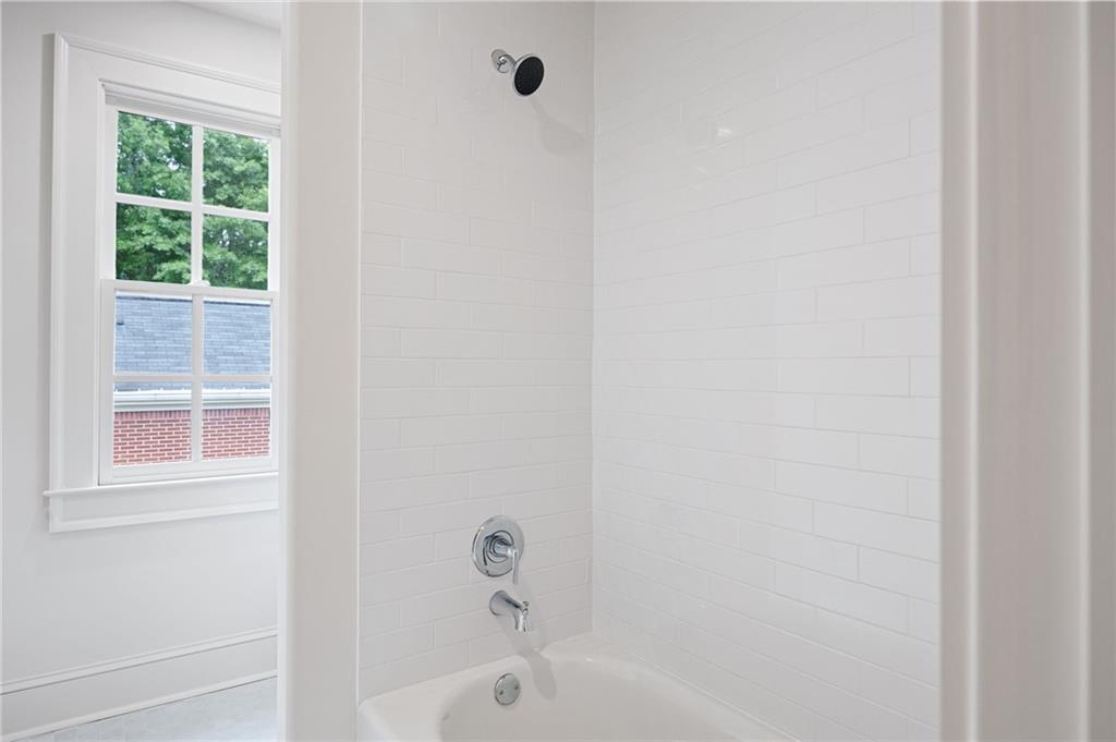 White tiled tub and shower beside a divided-pane window.