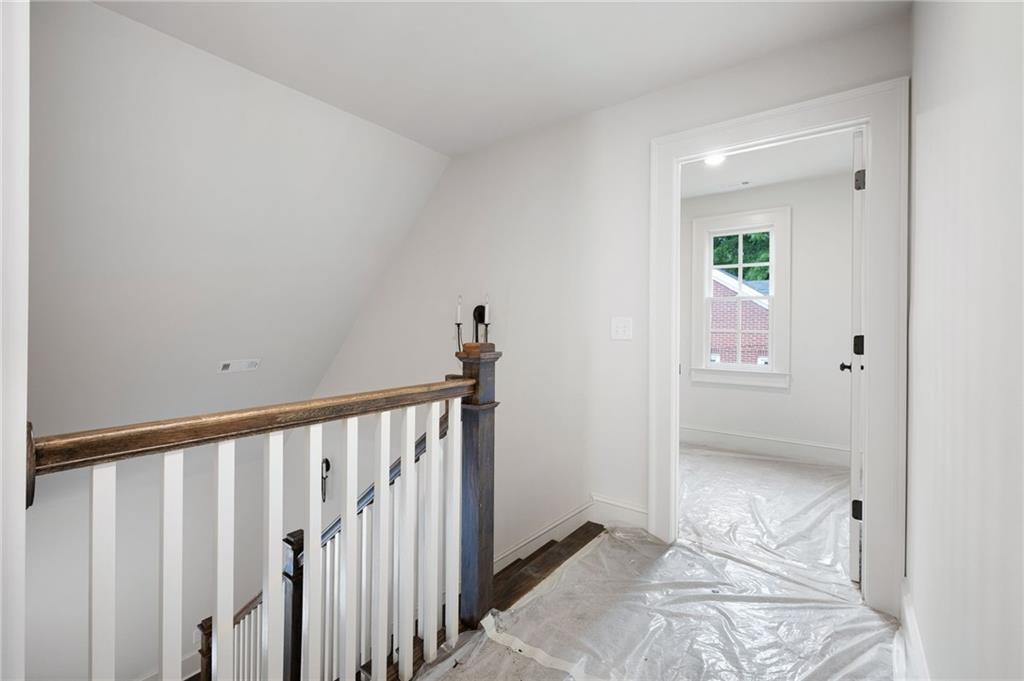 Upstairs landing with dark wood stair railing and protective plastic covering the floor.