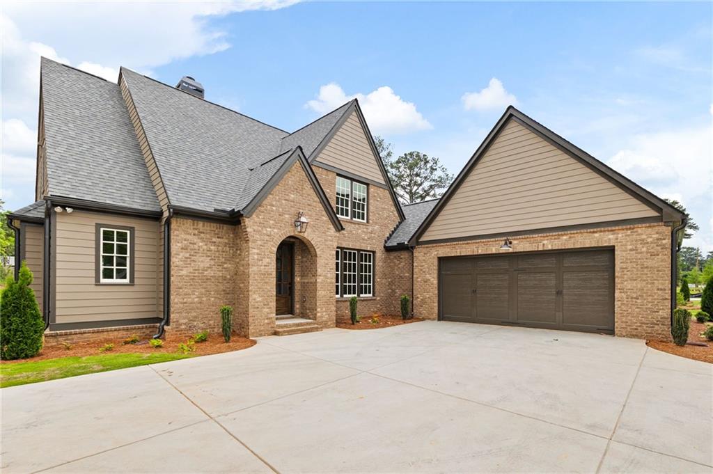 Brick and tan-sided home with an arched entry, steep gables, and a wide two-car garage.