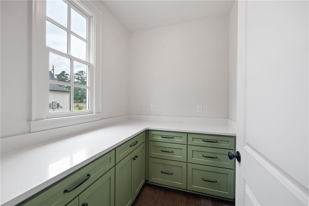 Kitchen workspace with green cabinets, white countertops, and a large multi-pane window.