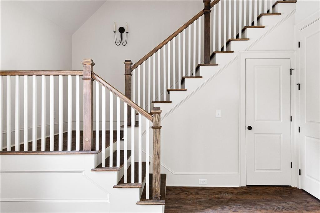 Entry hall with a split staircase, dark wood treads, white balusters, and hardwood floors.
