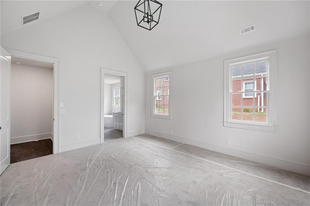 Empty bedroom with two windows, a geometric pendant light, and protective sheeting over the floor.