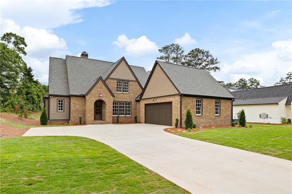 Brick and taupe-sided home with prominent gables, an attached garage, and a wide concrete driveway.