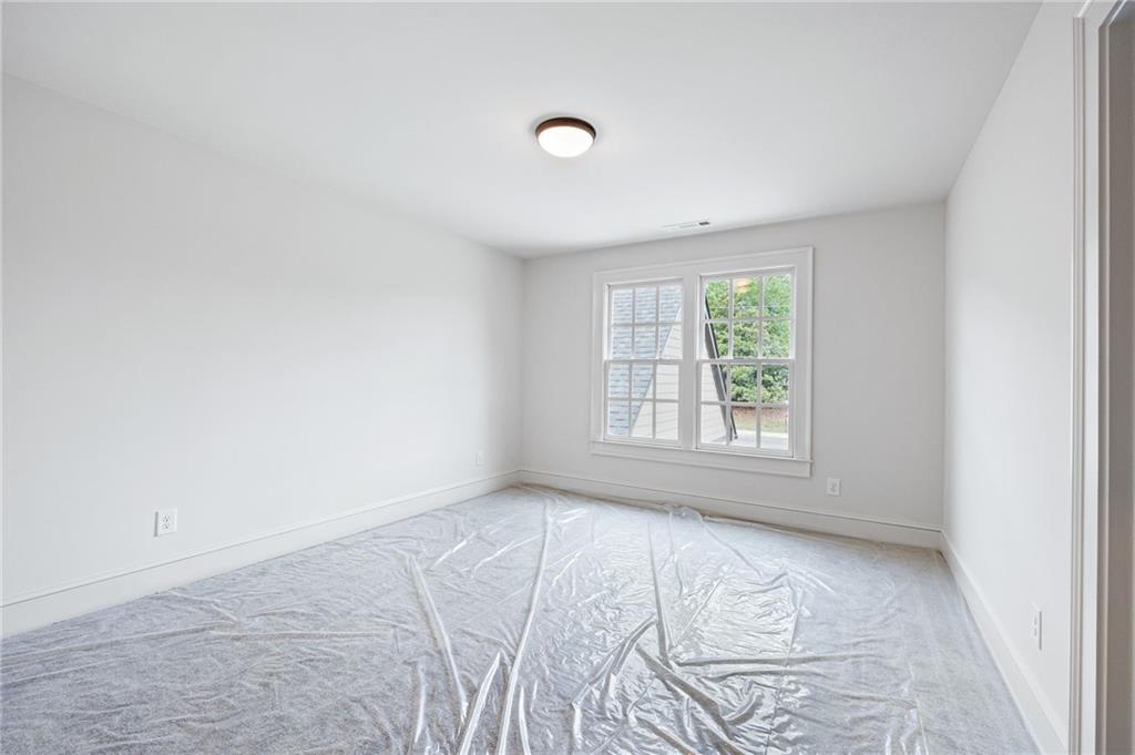 Empty bedroom with a double window and carpet covered in protective plastic.