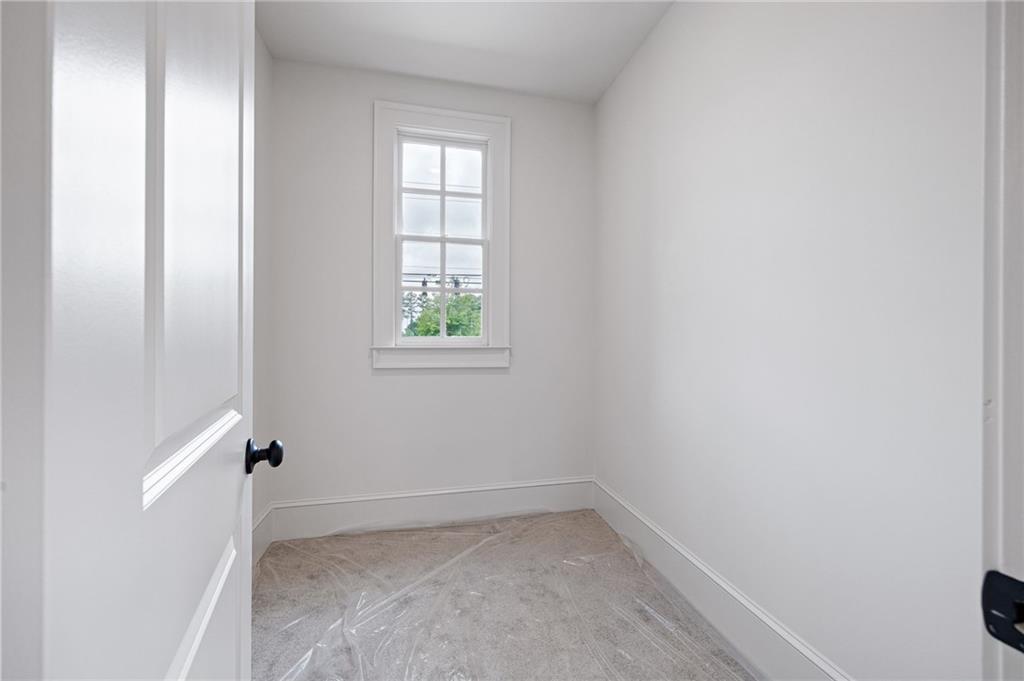 Small empty white room with a divided-pane window and protective sheeting over the floor.