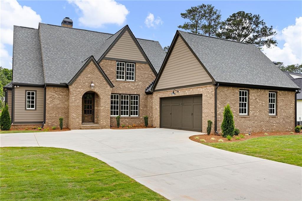 Brick house with steep gables, an attached garage, and a wide driveway.