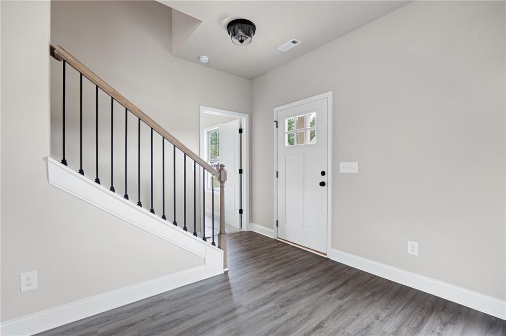 Entryway with gray flooring, a white front door, and a staircase with black balusters.