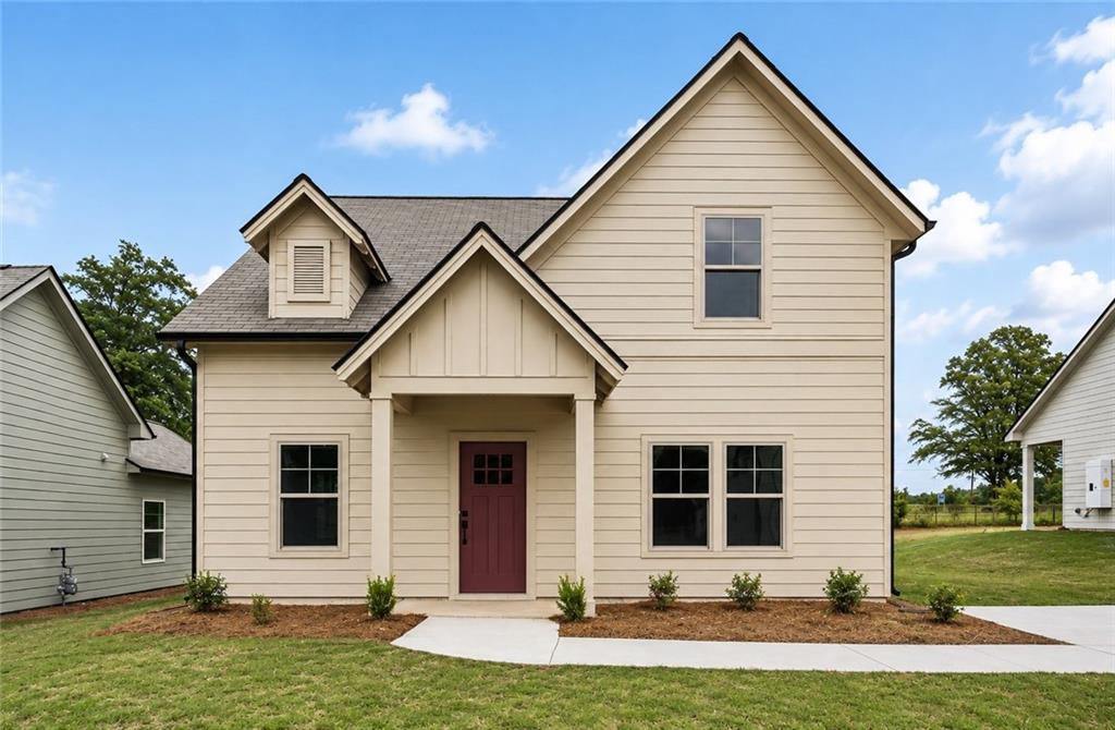 Two-story beige house with prominent gables, a covered entry, and a red front door.