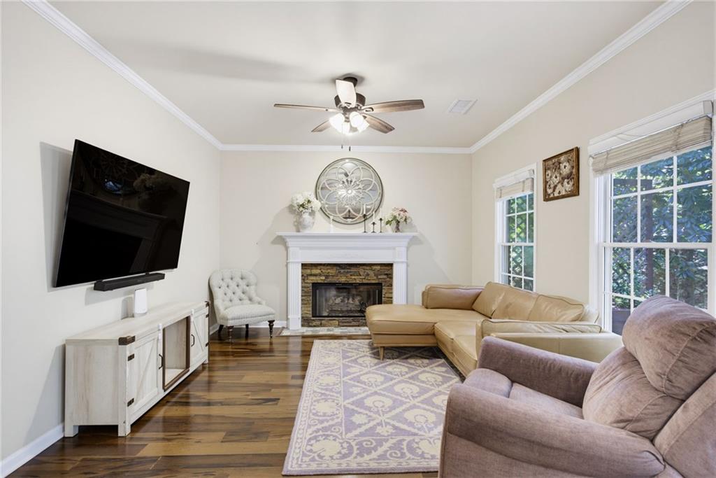 Living room with a stone fireplace, hardwood floors, and large windows.