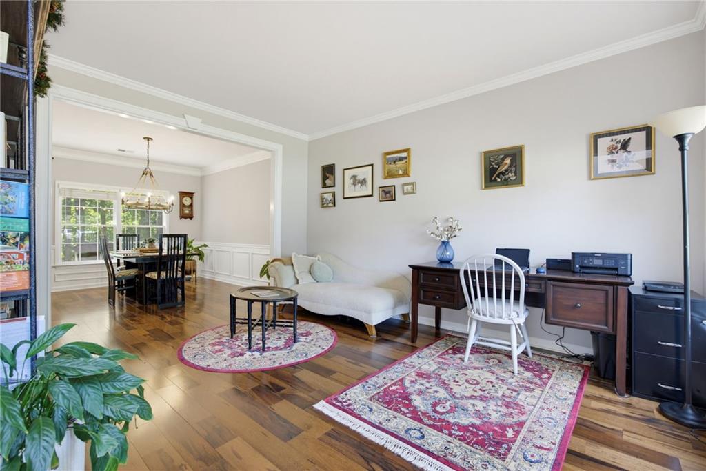 Living room with hardwood floors, patterned rugs, white sofa, and adjoining dining area.