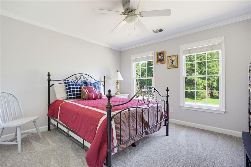 Bedroom with a black metal four-poster bed, pink bedding, and two windows overlooking greenery.