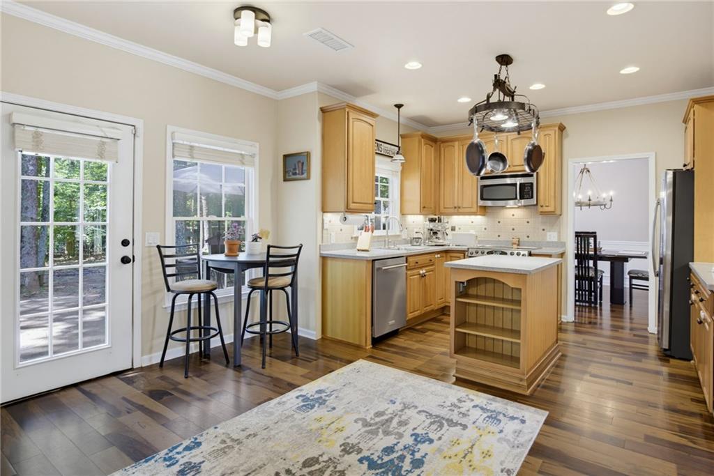Kitchen with wood cabinetry, stainless appliances, and an island beside a glass-paneled door.