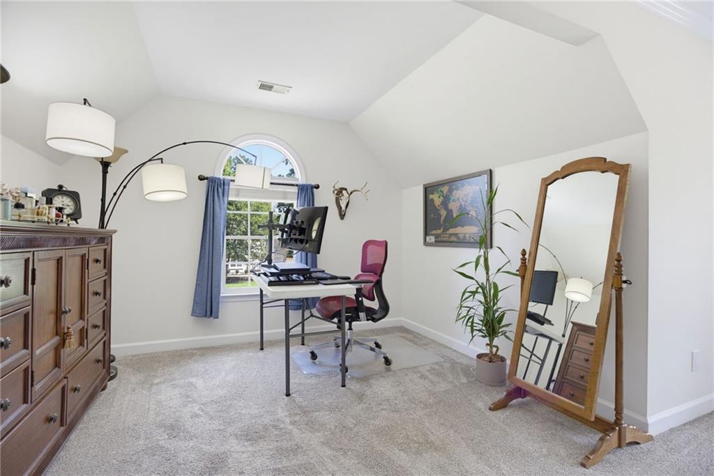 Furnished home office with a computer desk, arched window, and large leaning mirror.
