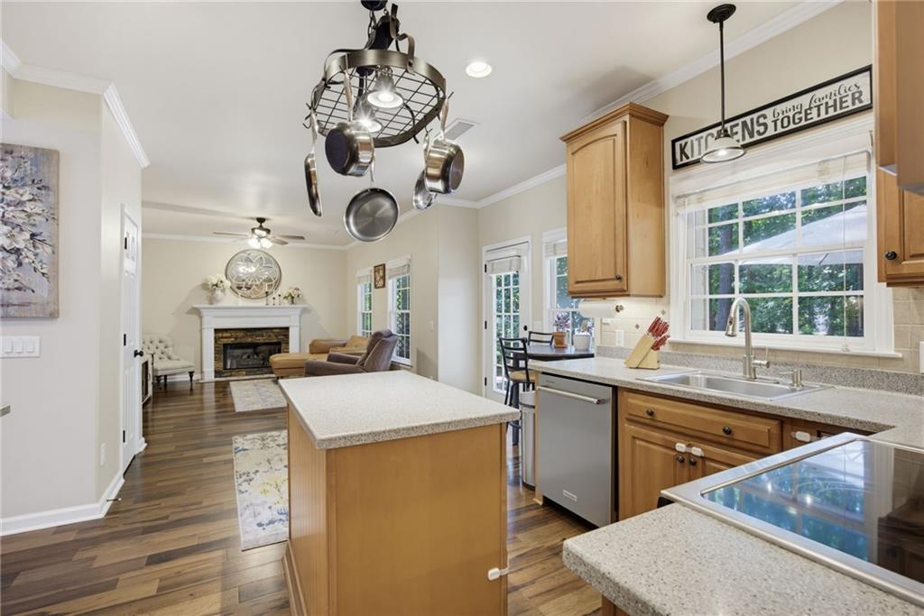Kitchen with a central island and wood cabinetry opening onto a living room with a fireplace.