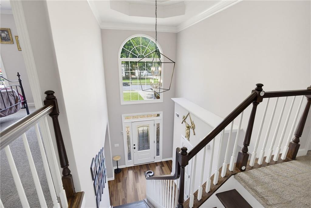 Two-story foyer with an arched window above the front door and a carpeted staircase with dark wood railings.