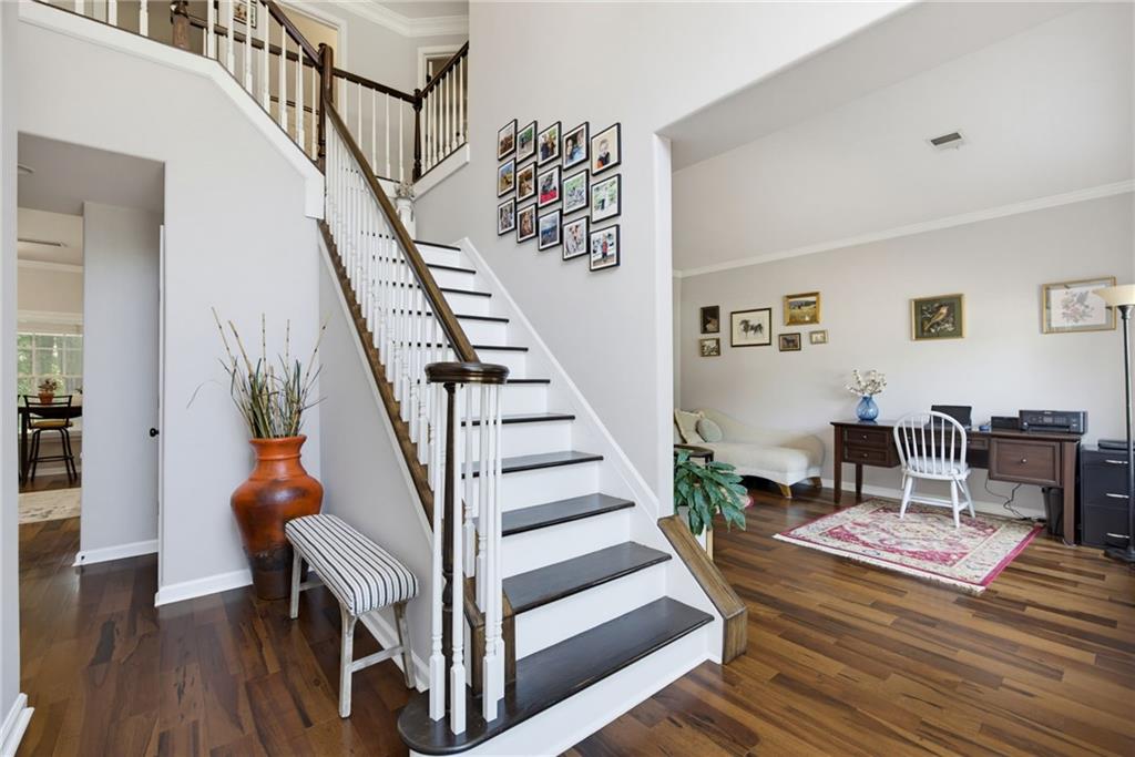 Two-story foyer with a white staircase, dark treads, hardwood floors, and an adjoining furnished sitting room.