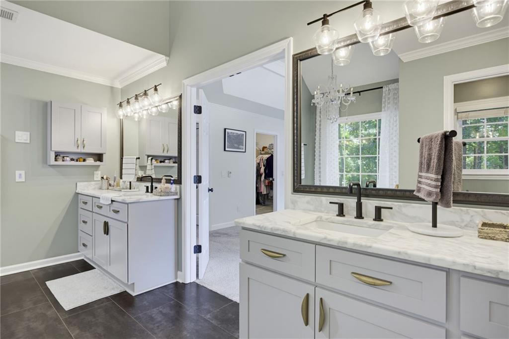 Bathroom with dual marble vanities, gray cabinetry, black faucets, and dark tile flooring.