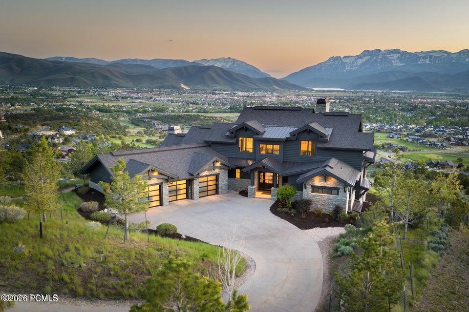 Large mountain-view home with stone accents and a curved driveway, photographed at dusk.