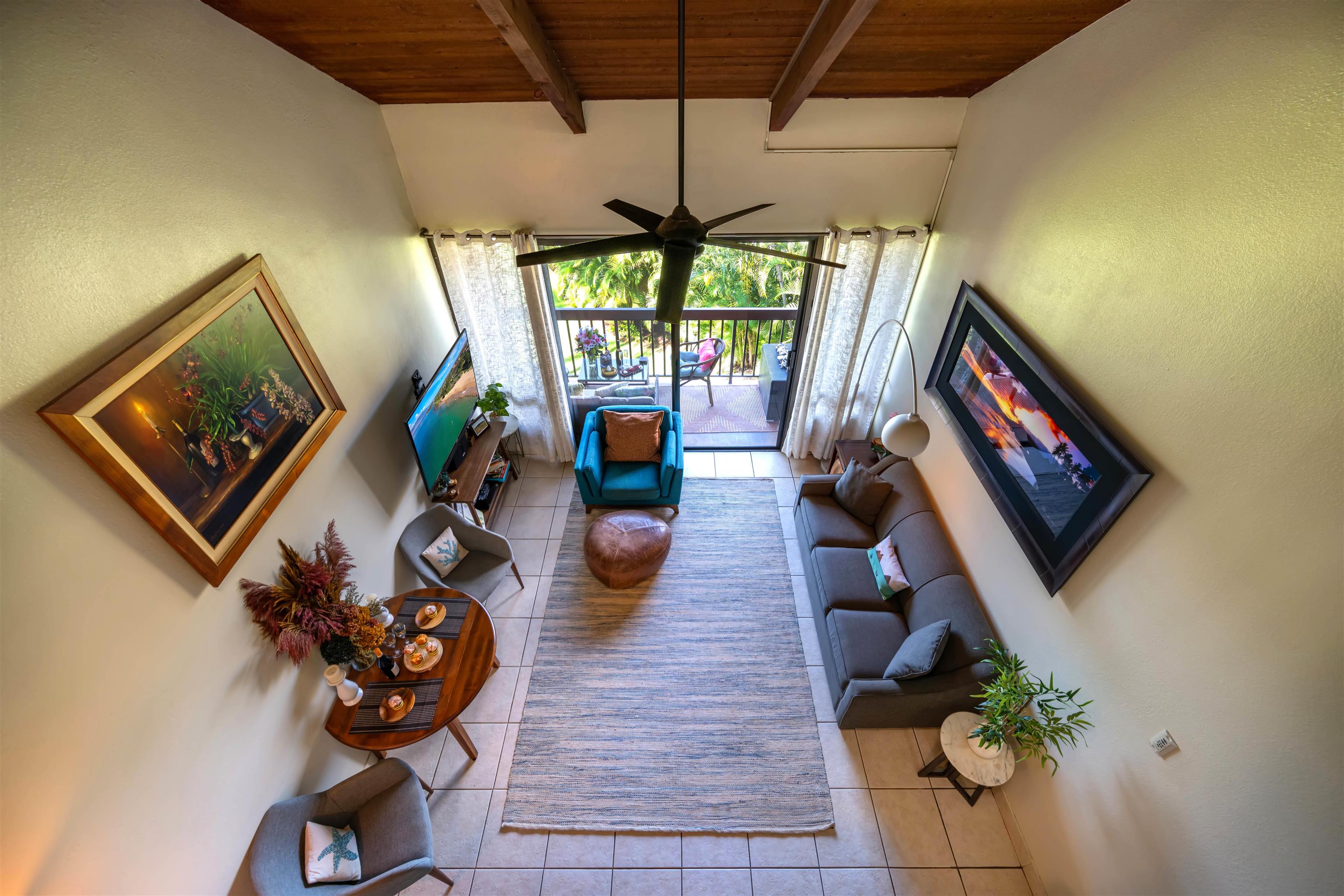 Furnished living room with a vaulted wood ceiling and sliding doors to a tropical balcony.