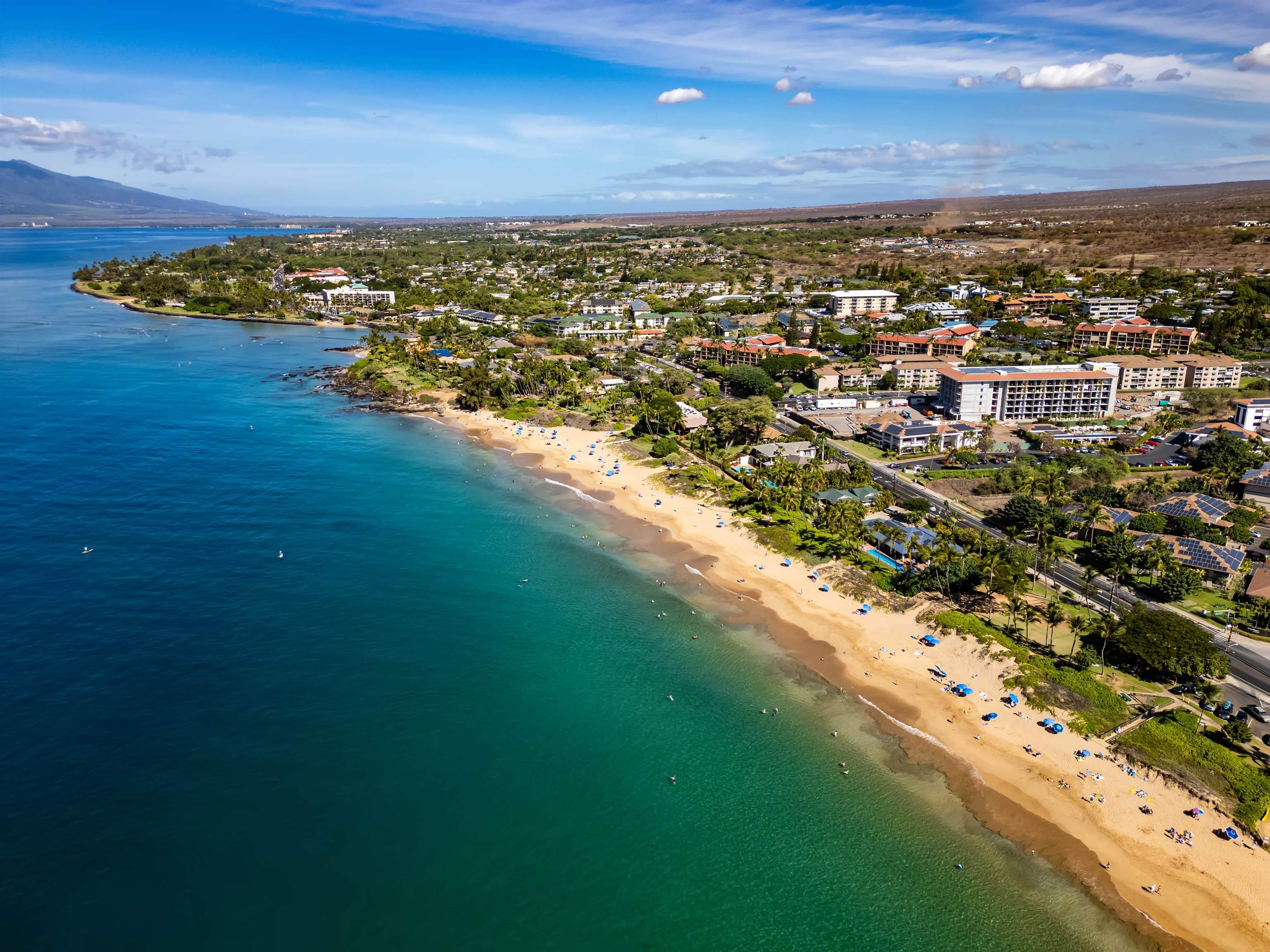 Aerial view of Kihei’s sandy coastline, turquoise water, and beachfront resorts.