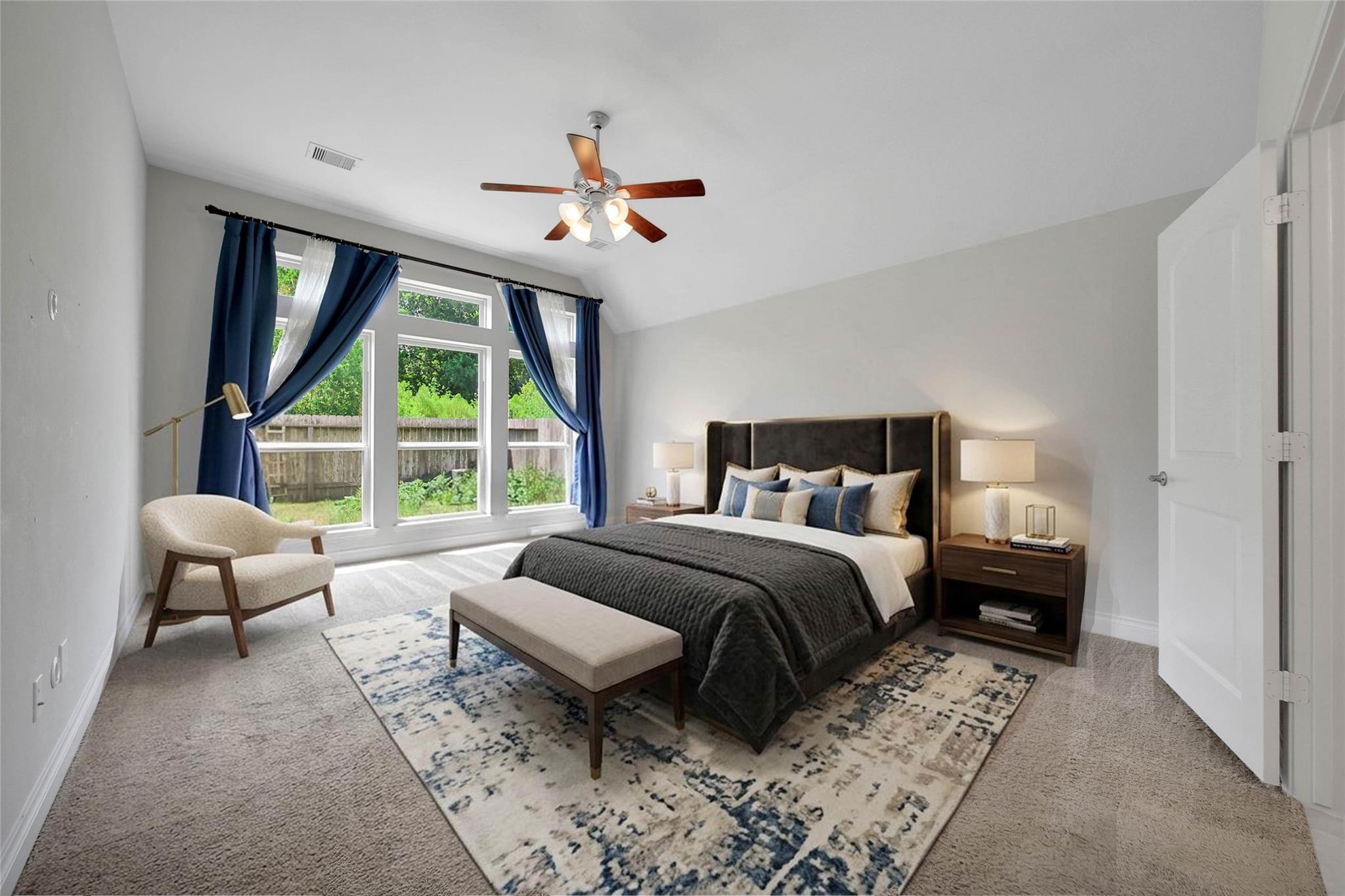 Staged bedroom with a dark upholstered bed, navy curtains, and tall windows overlooking a leafy yard.