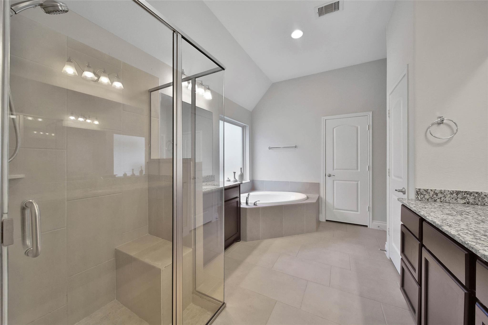Spacious bathroom with a glass walk-in shower, built-in soaking tub, and granite-topped vanity.