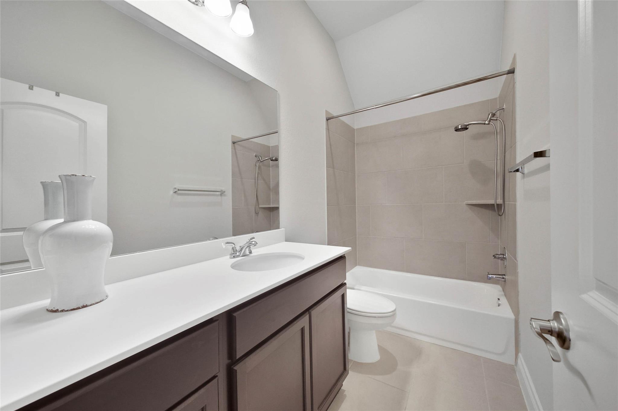 Bathroom with a dark wood vanity and tiled tub-shower combination.