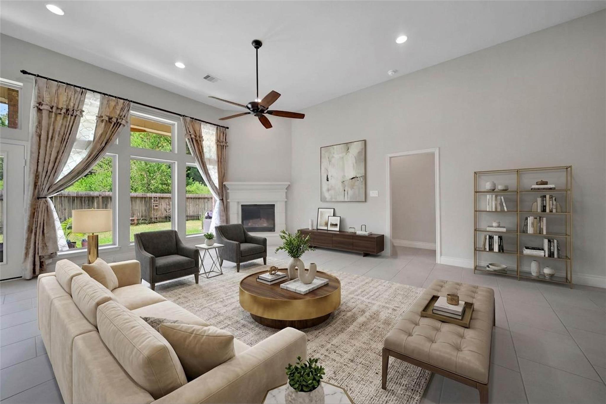 Living room with tall backyard-facing windows, a fireplace, and neutral seating.