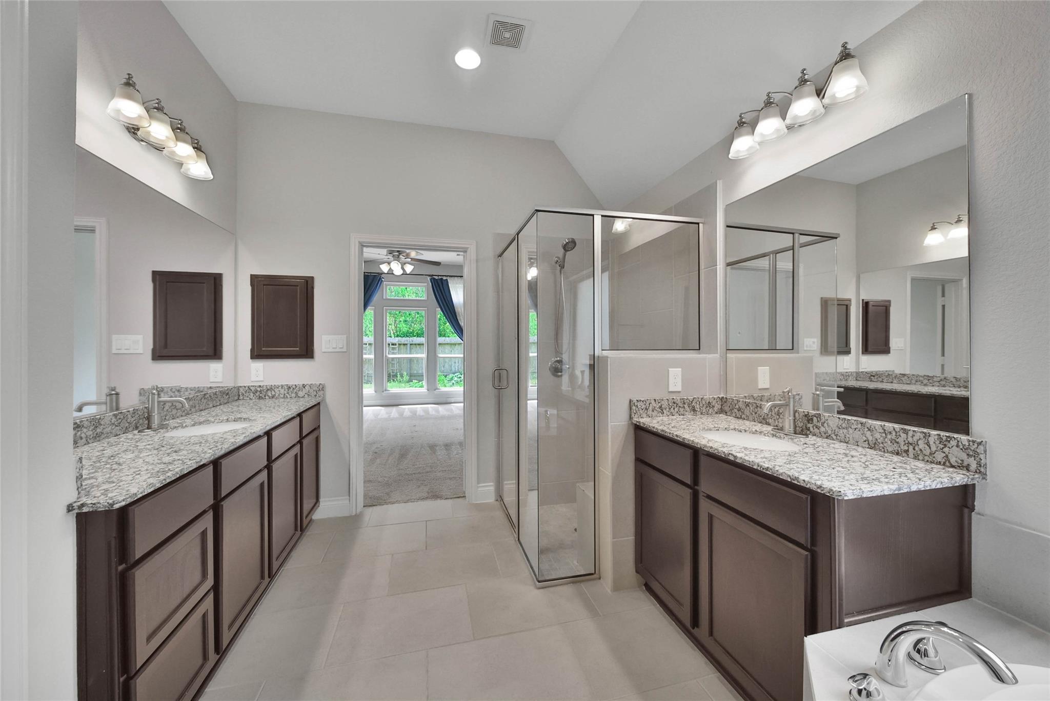 Primary bathroom with dual granite vanities and a glass-enclosed shower.