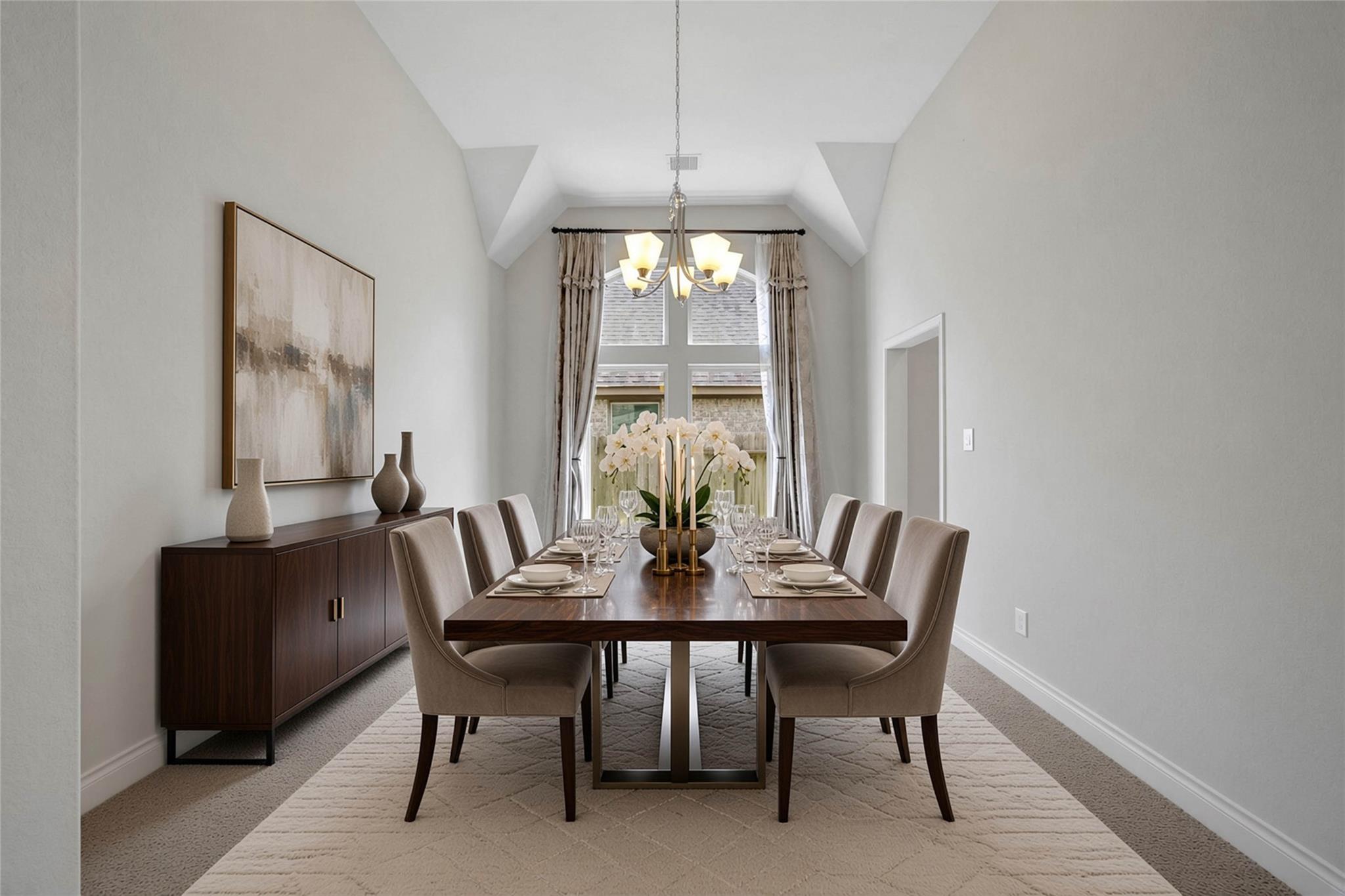 Dining room with a set table, upholstered chairs, chandelier, and vaulted ceiling.