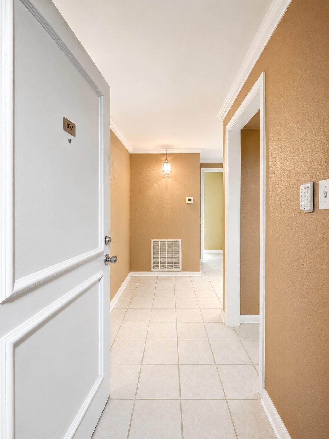 Tiled condo entry hall with the white door marked 107 open.