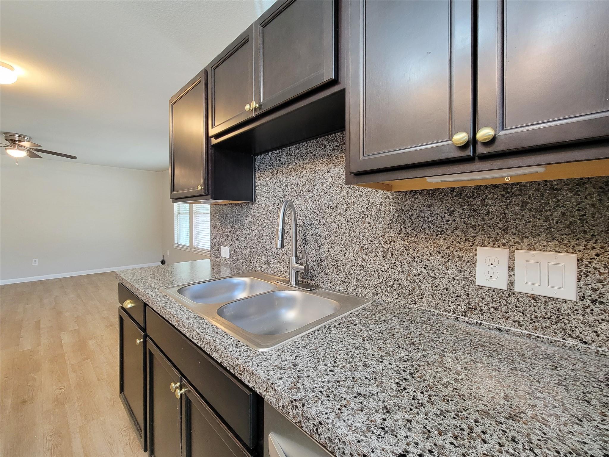 Kitchen with dark cabinets, speckled countertops, and a double-basin sink.