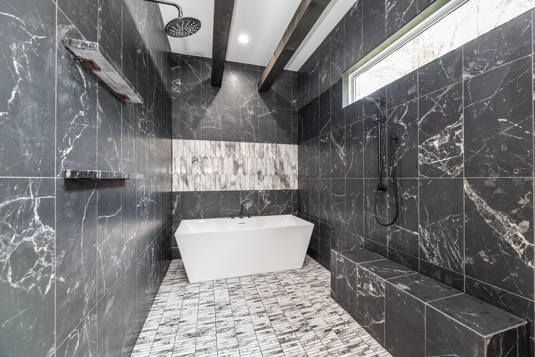 Modern bathroom with freestanding tub, dark marble-look tiles, and a walk-in shower with built-in bench.