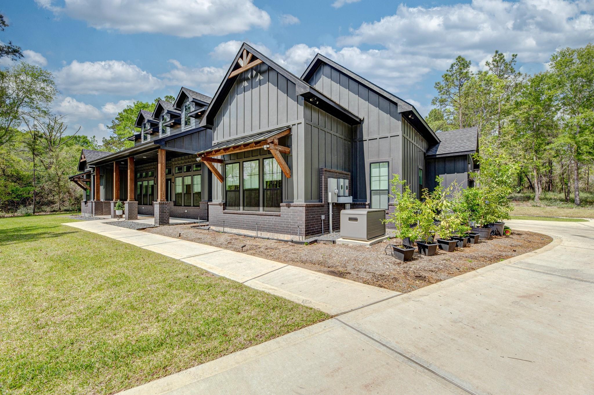 Modern dark-gray home with multiple gables, a timber-supported porch, and a wide concrete driveway.