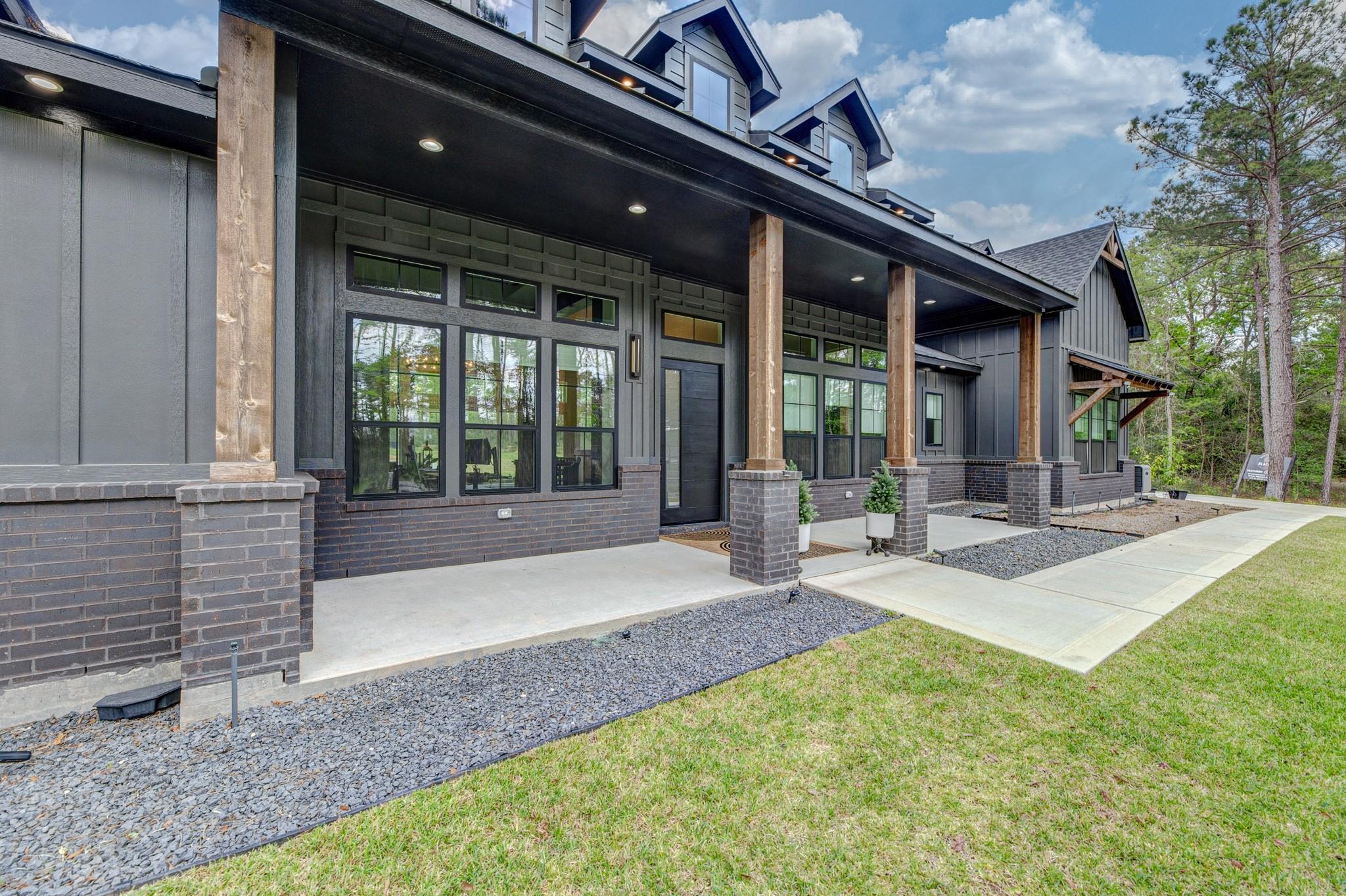 Modern dark-gray house with a deep covered porch, timber columns, and tall windows.