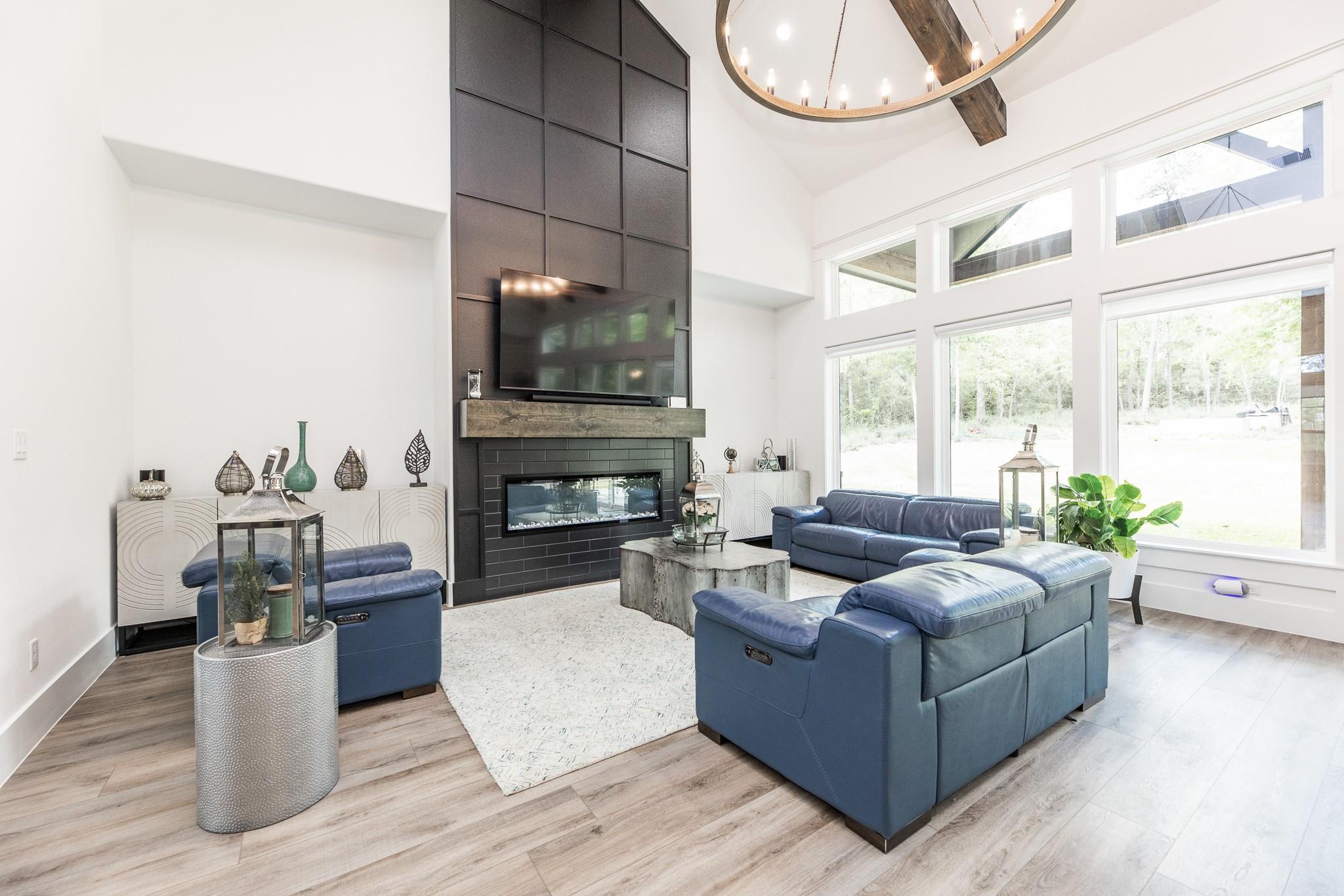 Bright living room with blue sectional sofas, expansive windows, and a modern fireplace.