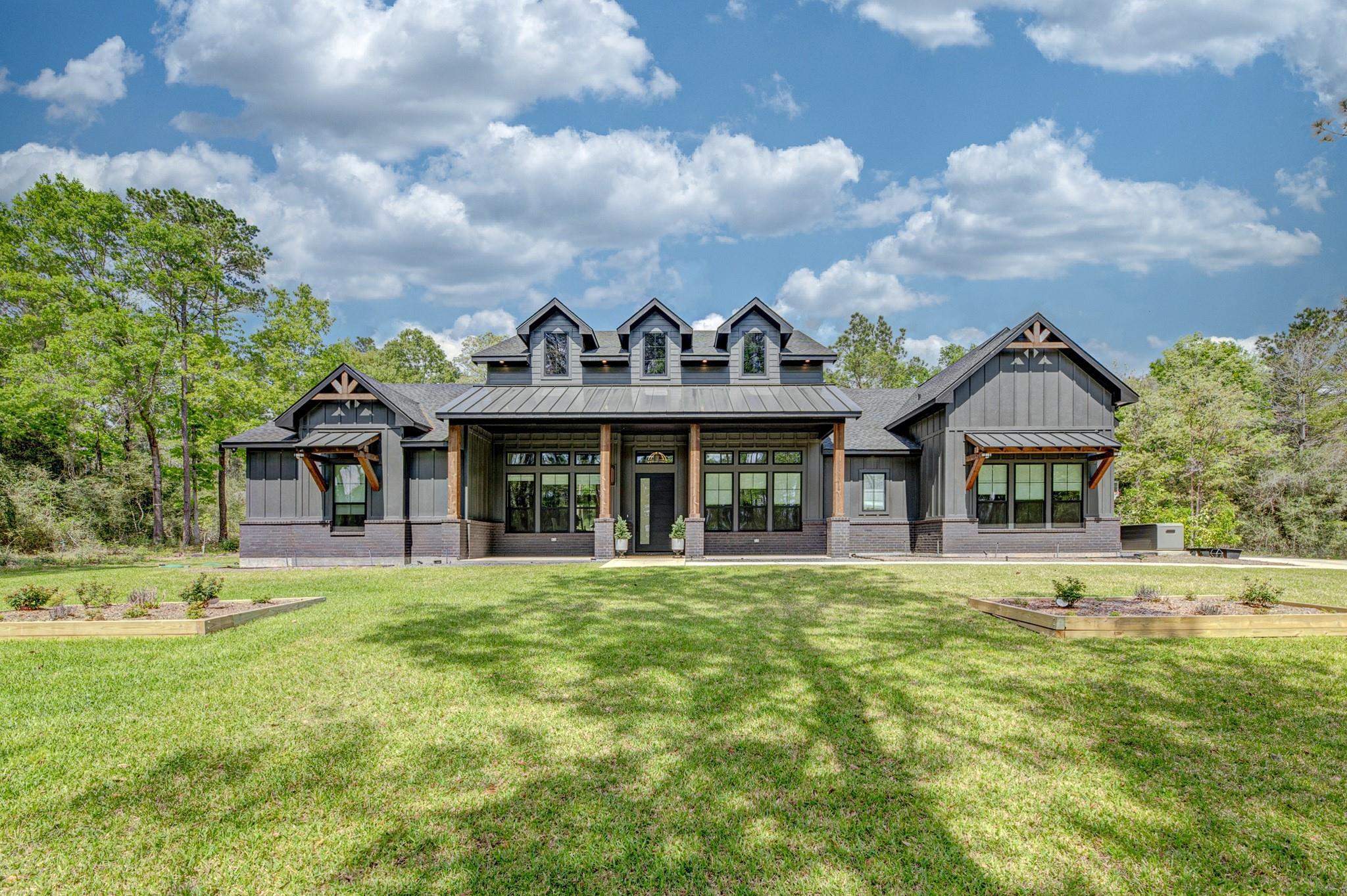 Modern gray house with three dormers and a covered porch, set behind a broad green lawn.