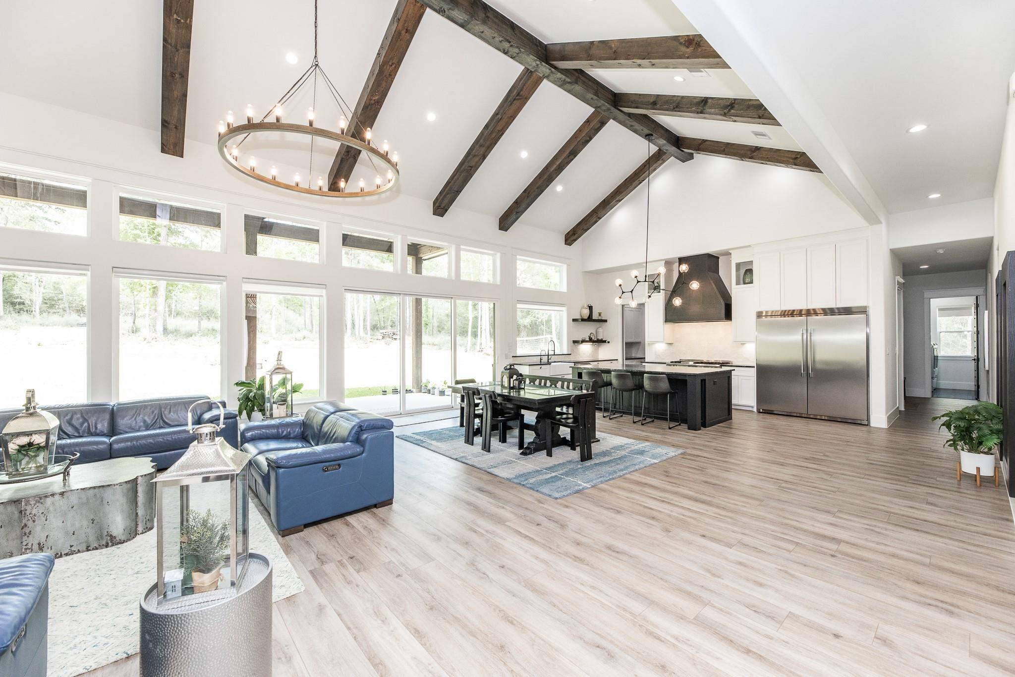 Open living and dining area with blue leather seating, vaulted wood-beam ceiling, and adjoining kitchen.
