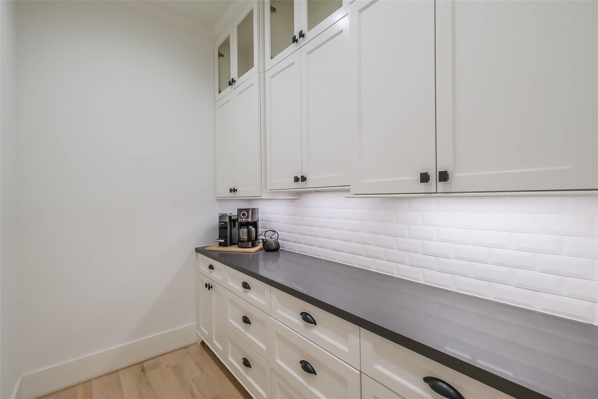 Kitchen with white cabinets, dark countertops, subway tile backsplash, and a coffee station.