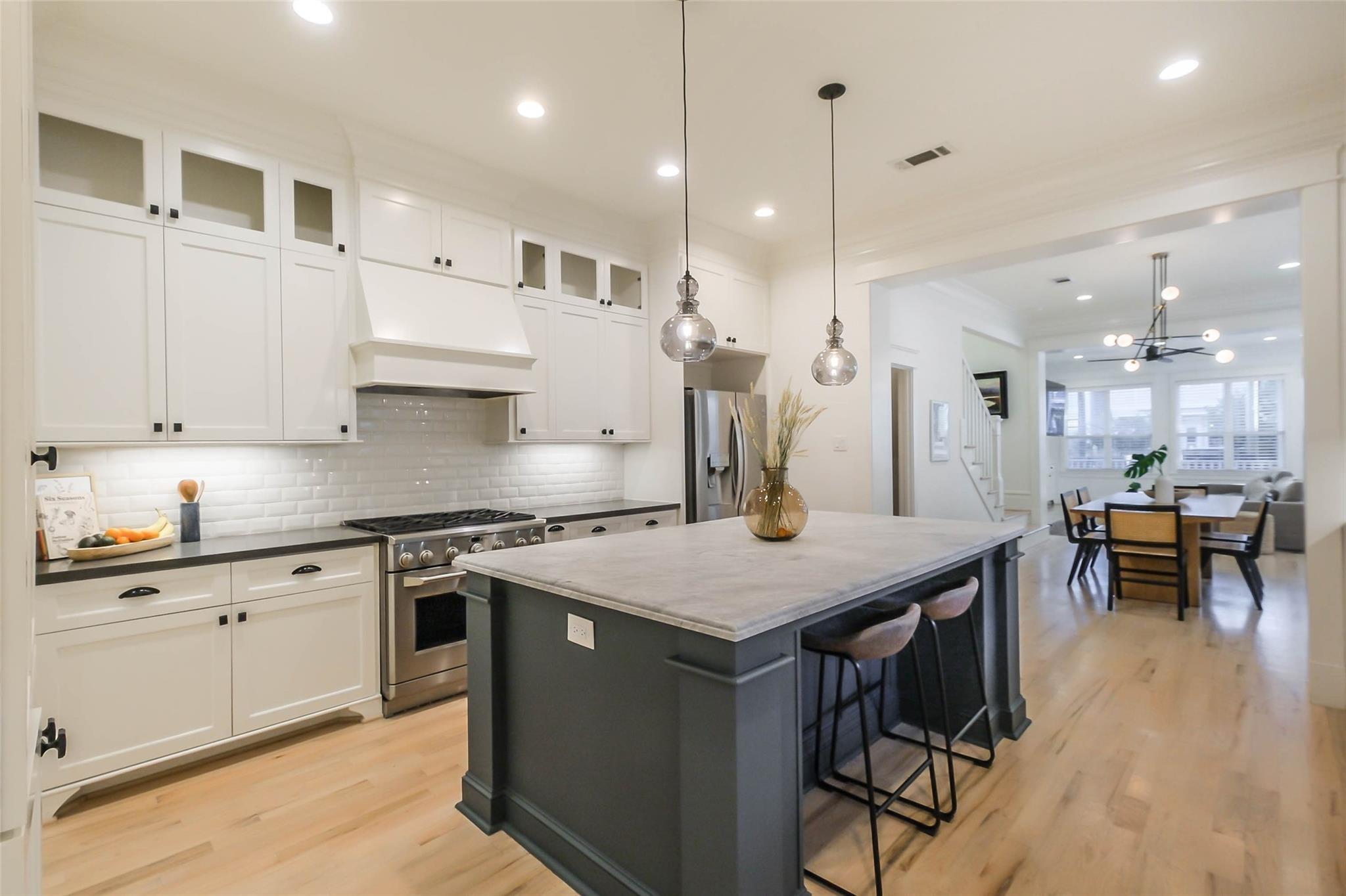 Bright kitchen with white cabinets, a large dark island, and an adjoining dining area.