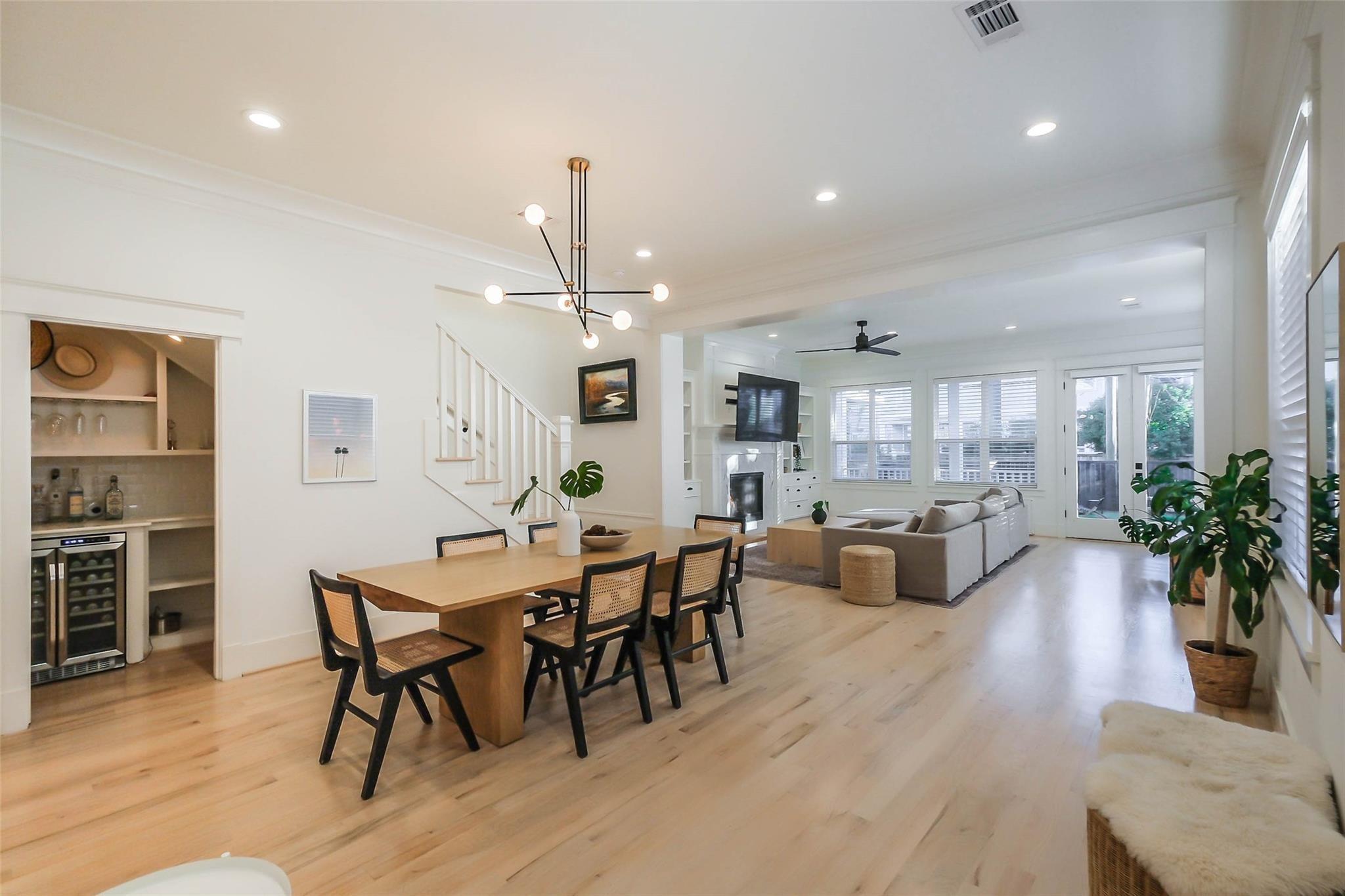 Open-plan dining and living area with a built-in bar nook and light wood floors.