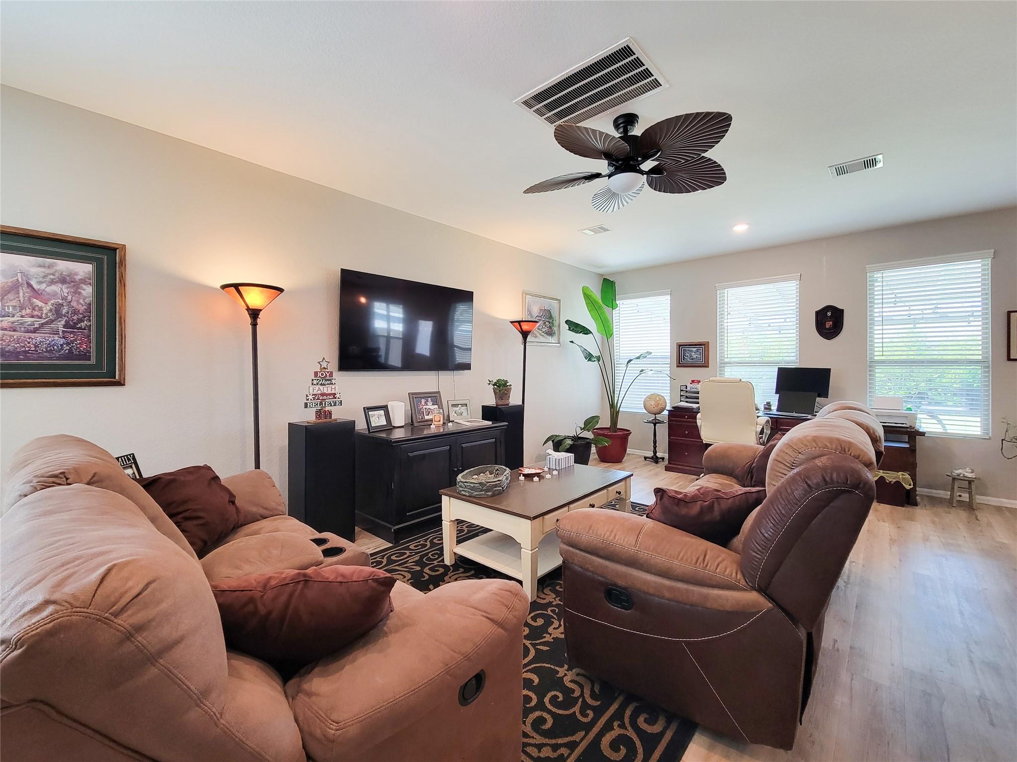 Furnished living room with tan sofas, a brown recliner, and a wall-mounted television.