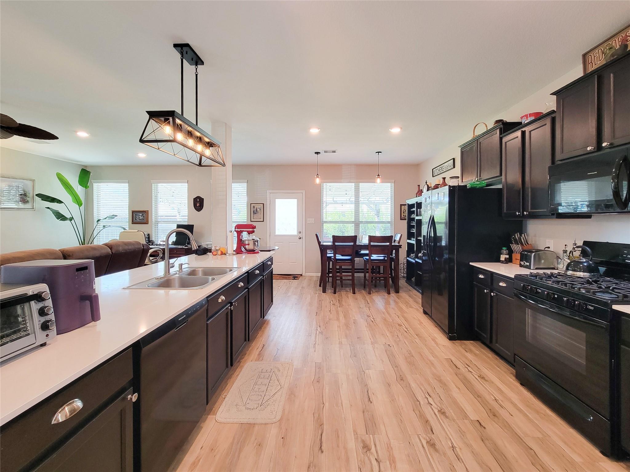 Open-plan kitchen with a large white island, dark cabinetry, and an adjoining dining table.