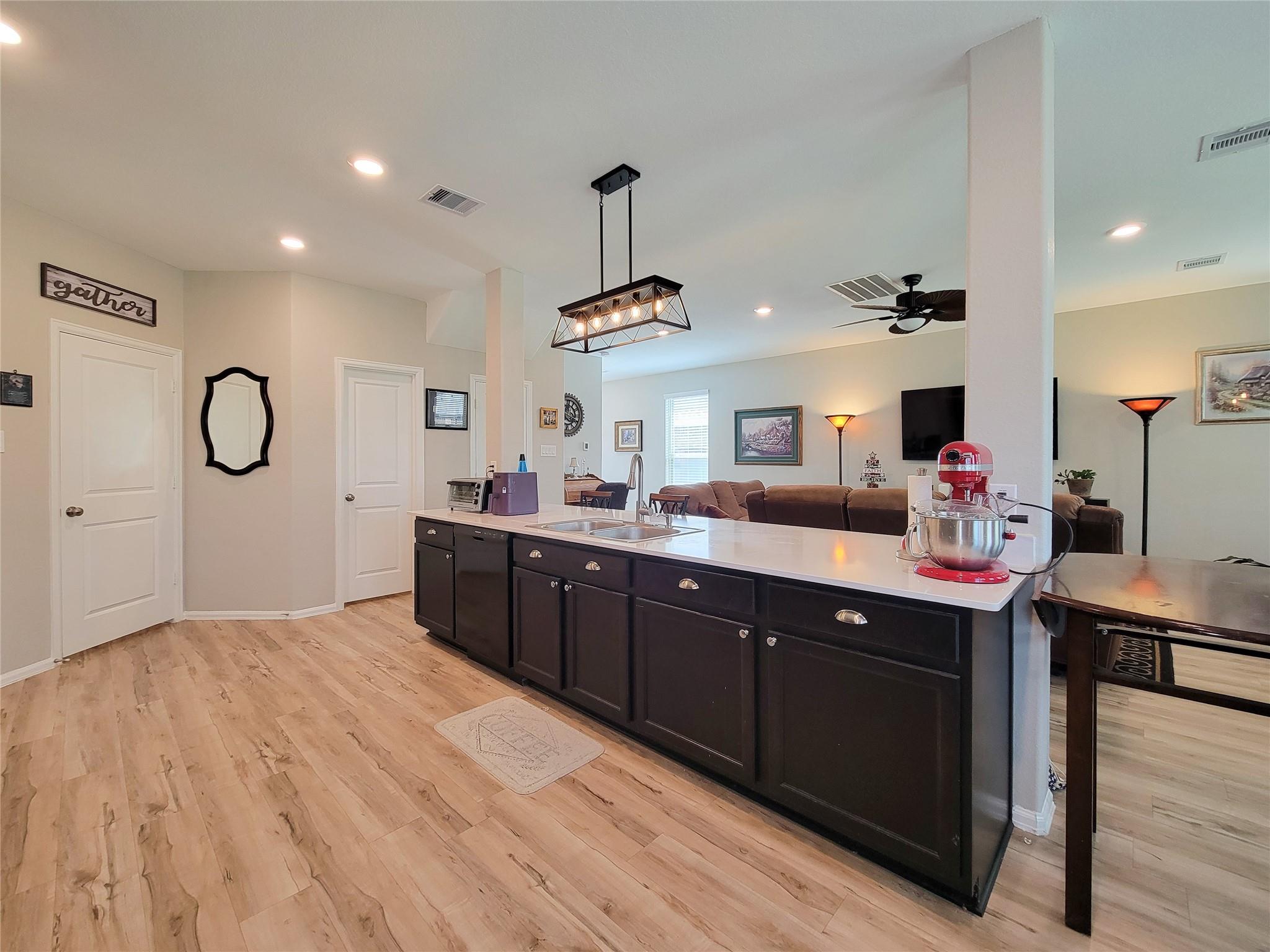 Open-plan kitchen with a large dark-cabinet island and living room beyond.