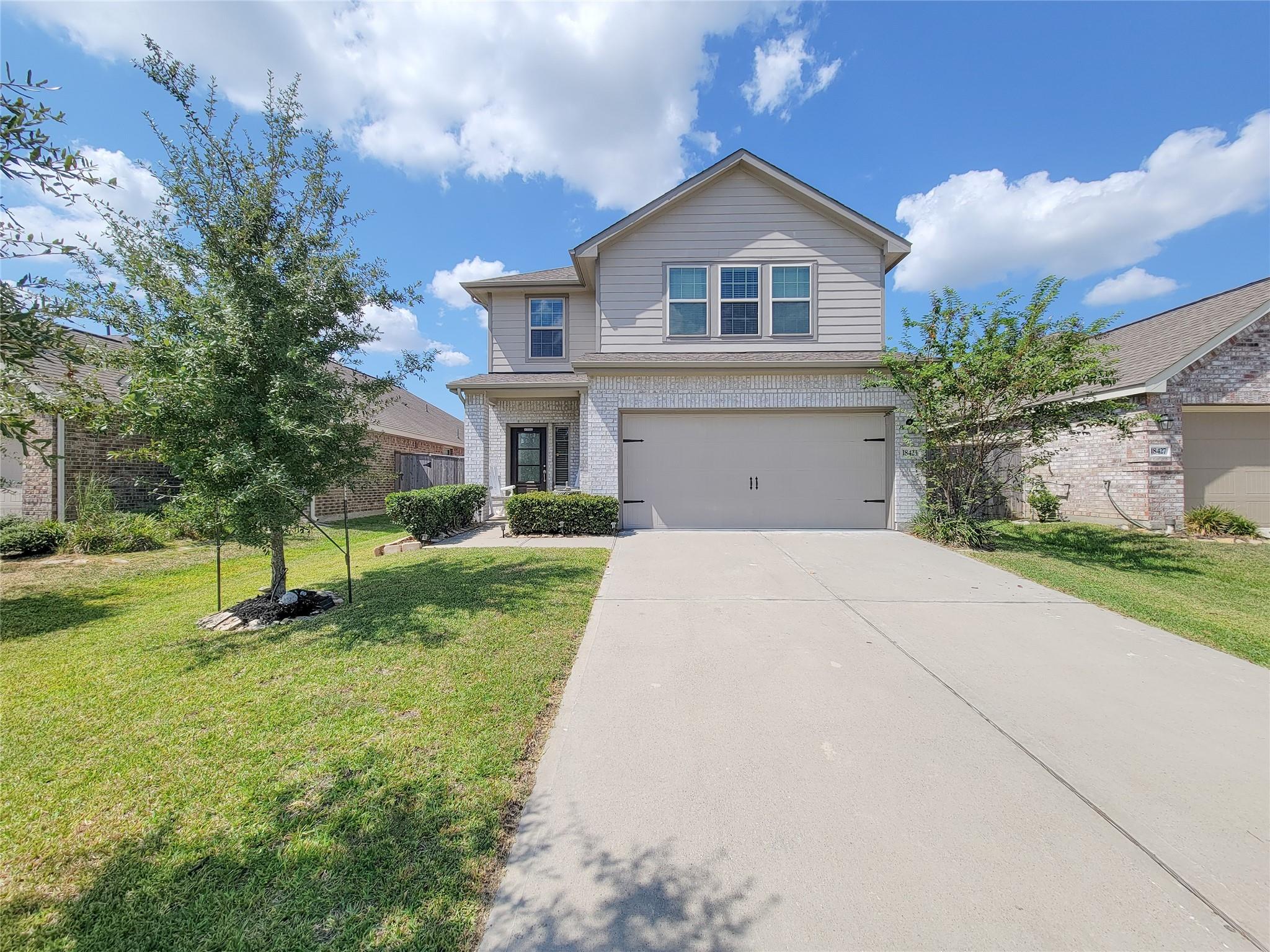 Two-story gray-sided and white-brick home with a two-car garage and wide driveway.