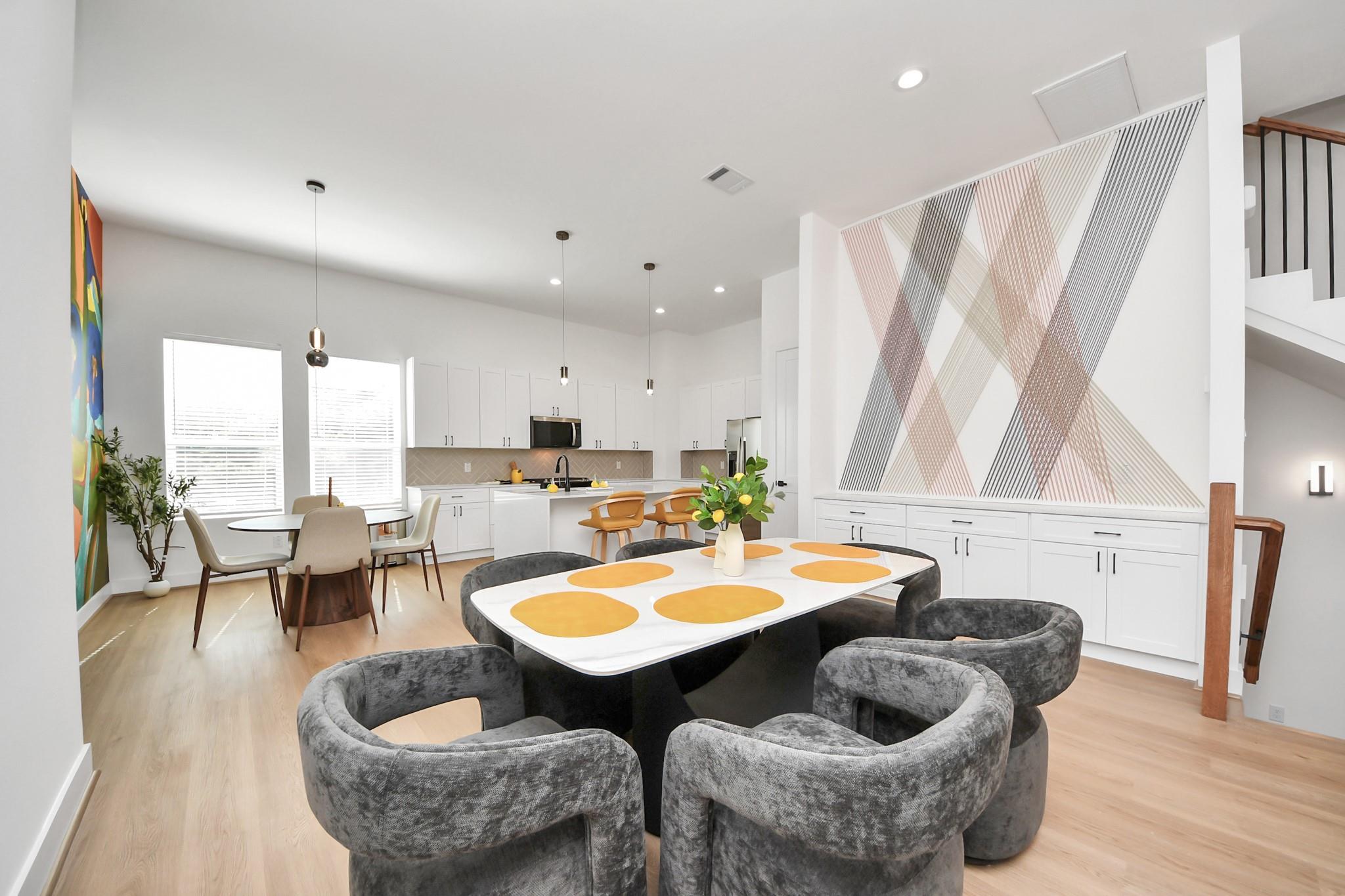 Open-plan kitchen and dining area with white cabinetry and a large geometric wall installation.